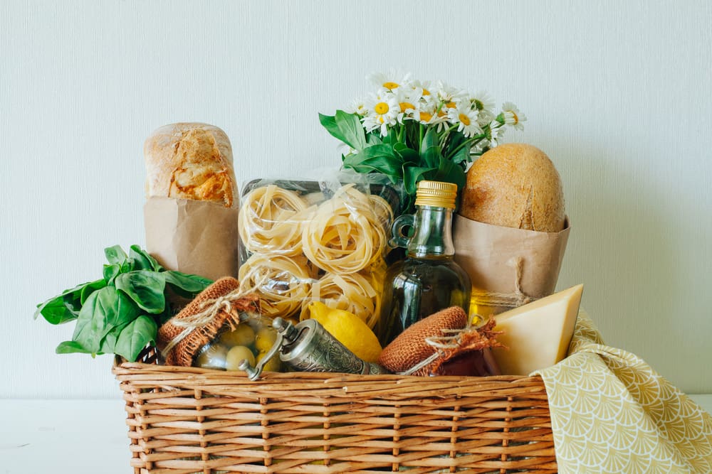 装满面包、奶酪、鲜花和一罐蜂蜜的健康礼物篮。