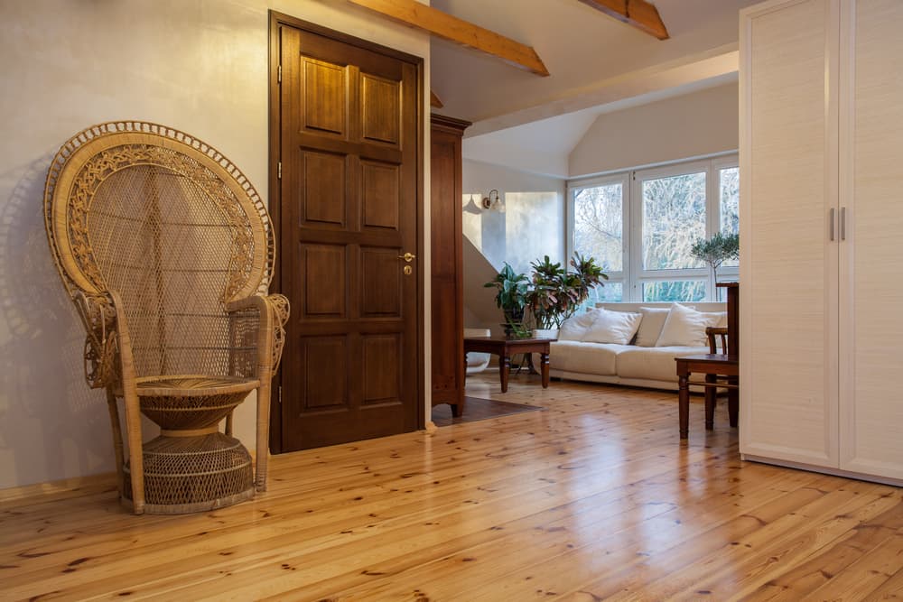 舒适的起居区，有横梁天花板，松木地板上有一把大柳条扶手椅。