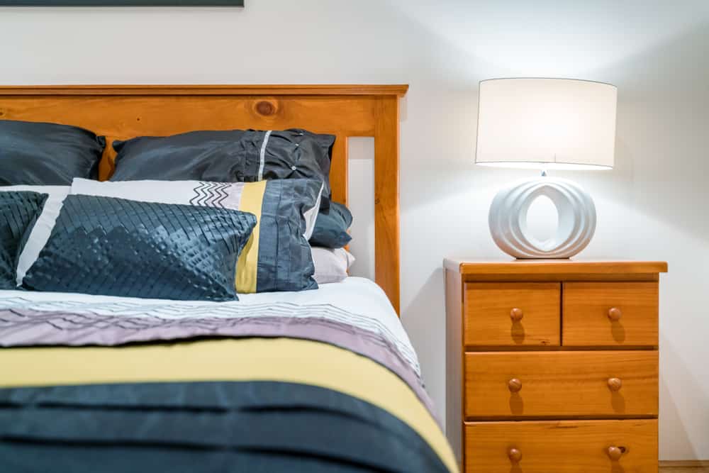 由松木制成的床和配套的床头柜，上面有一盏现代台灯。