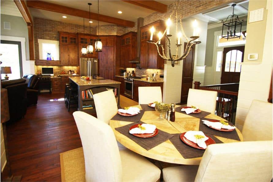 餐厅与蜡烛吊灯和一个圆形的餐桌搭配米色软垫椅子。