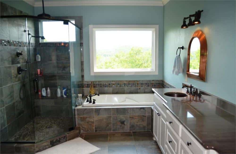 主浴室有一个双水槽梳妆台，一个步入式淋浴间，和一个落脚浴缸明亮的观景窗。