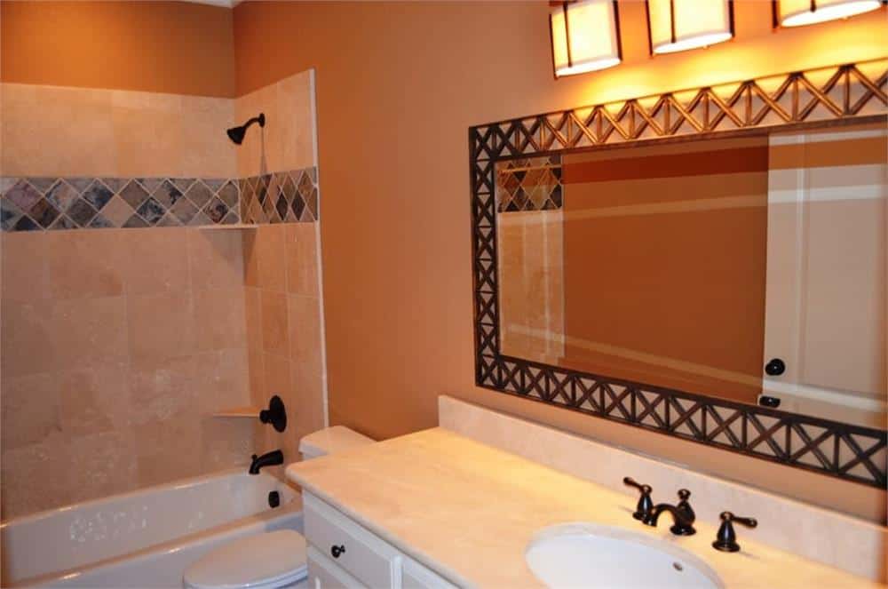 浴室配有水槽梳妆台和浴缸和淋浴组合，配有锻铁固定装置。