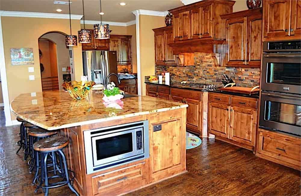 厨房配有天然木制橱柜、花岗岩台面和一个配有圆形吧台凳的大早餐岛。
