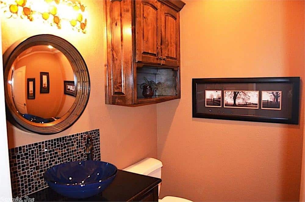 化妆室，桃色墙壁，一个挂柜，和一个容器水槽梳妆台顶部有一个圆形镜子。