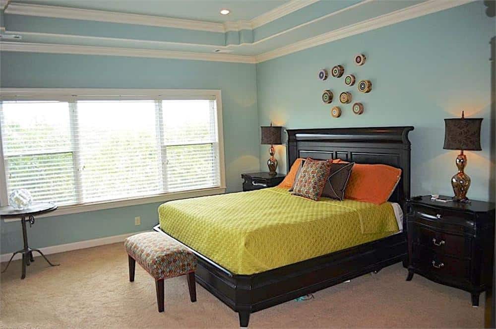 主卧室的特点是深色的木制家具，托盘天花板，浅蓝色的墙壁装饰着小的圆形墙壁艺术品。