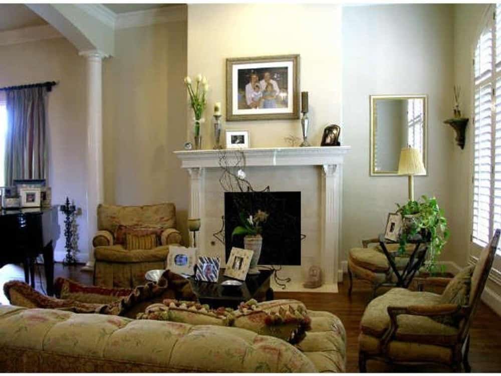 客厅里有壁炉、花椅子和一张黑木咖啡桌，上面放着相框的照片。