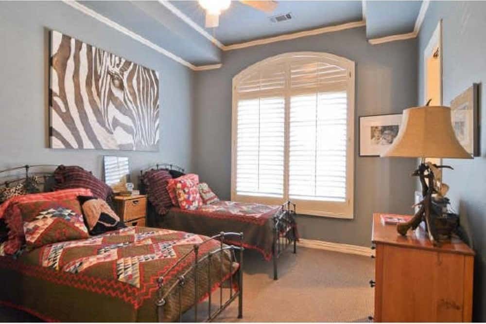 这间卧室有两张金属床，一个木制梳妆台，蓝色的墙壁上装饰着一幅巨大的斑马艺术品。