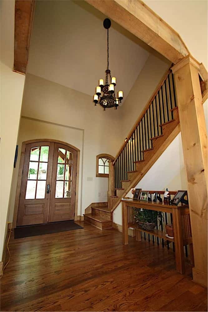 门厅设有法式入口门，并在传统楼梯旁放置了一张木制控制台桌子。