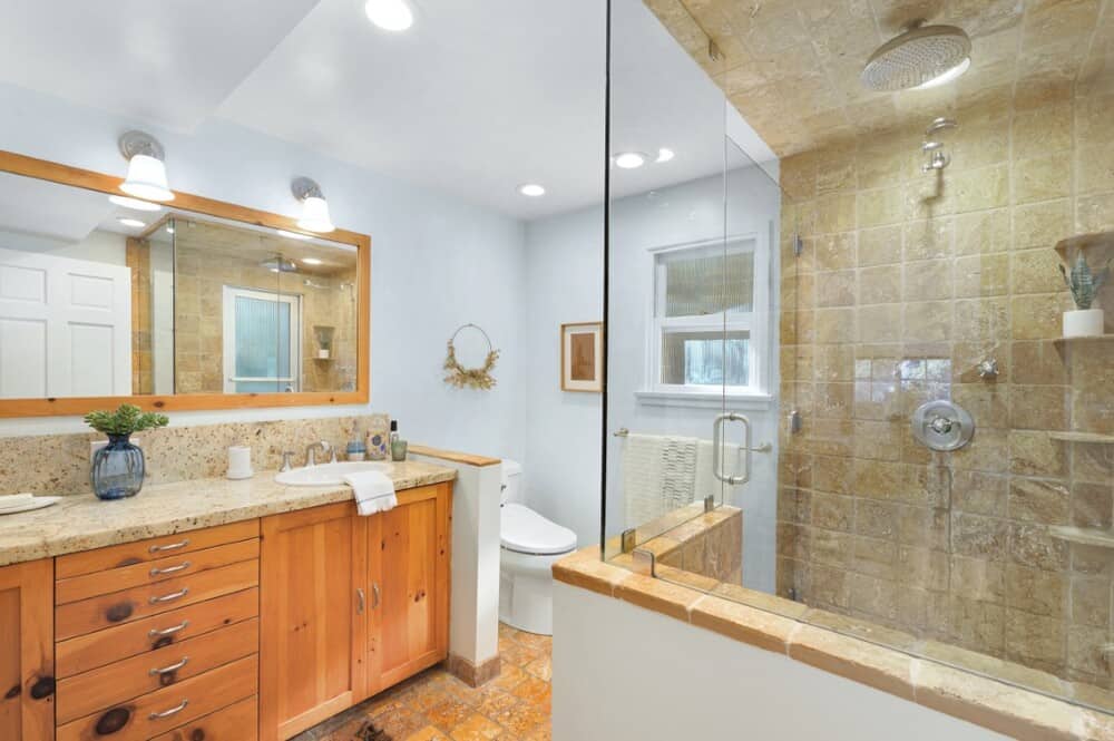 浴室里有一间玻璃围成的大型淋浴区，对面是梳妆台区，梳妆台上有木制橱柜，上面有一面大镜子。图片来自Toptenrealestatedeals.com