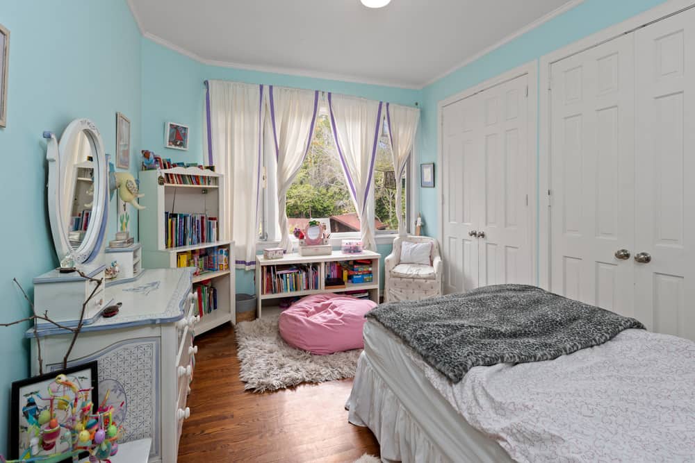 这是一间儿童卧室，有一张小床，对面是游乐区，有一张豆袋椅和书架。图片来自Toptenrealestatedeals.com