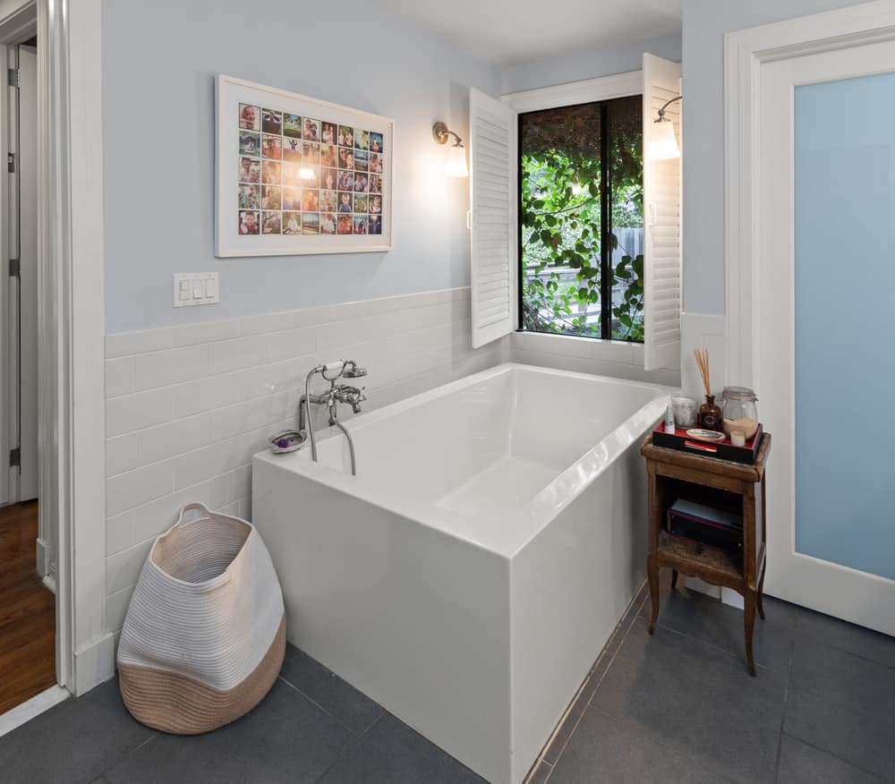 这是浴室梳妆台对面的角落浴缸，长方形的形状被窗户和烛台照亮。图片来自Toptenrealestatedeals.com
