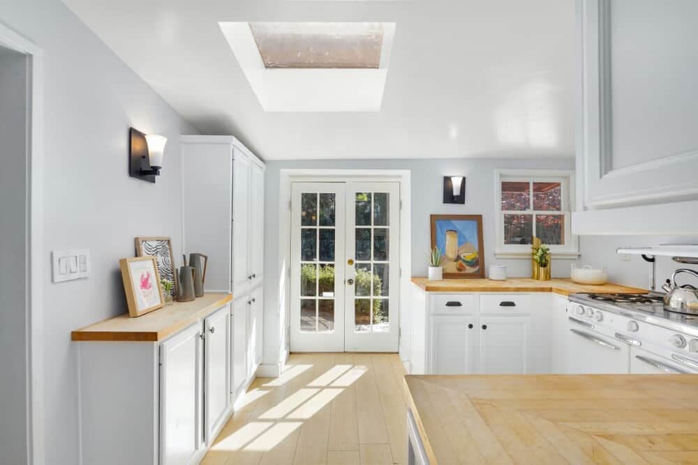 这是厨房的景观，白色的橱柜与木制柜台相搭配，法式门和天灯使其更加明亮。图片来自Toptenrealestatedeals.com