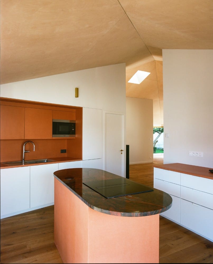 宽敞的厨房区域的内部视图，白色的墙壁和橱柜面板与中央台面。