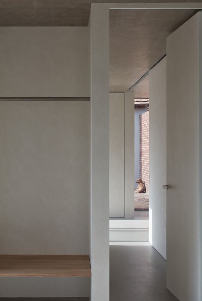 这是厨房远端走廊的近距离观察，两侧有白色结构和混凝土天花板。