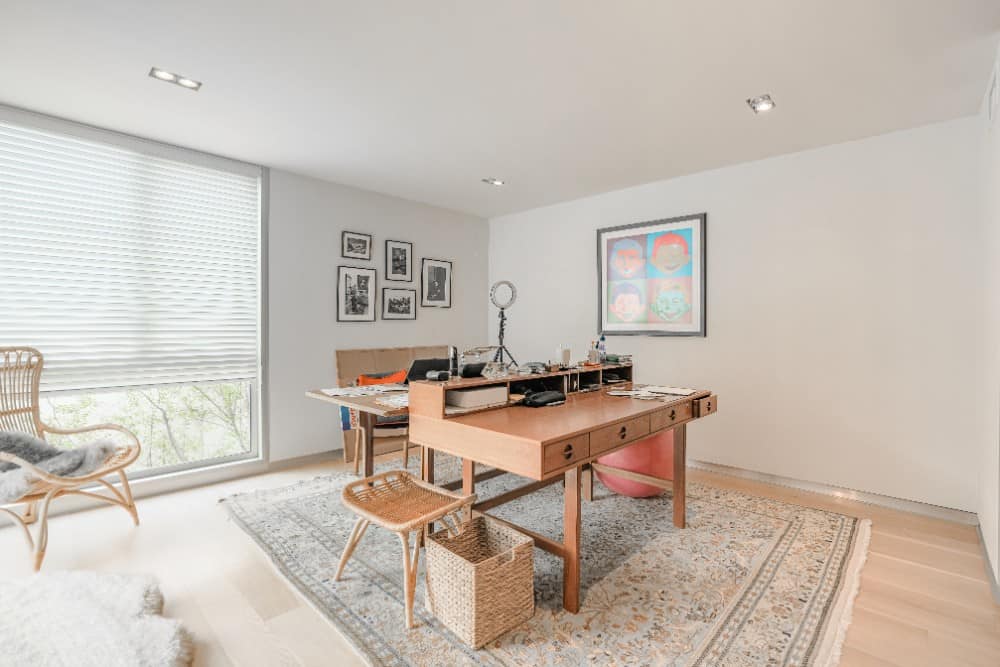 家庭办公室，有木桌，柳条座椅，浅色硬木地板上铺着流苏地毯。图片来自Toptenrealestatedeals.com。