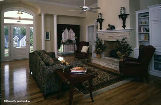 大房间里有一张花沙发和棕色的翼背椅，两侧是石头壁炉。