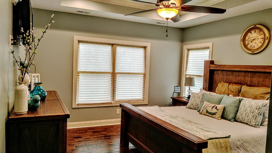 主卧室有木制家具，硬木地板，和一个装有传统风扇的托盘天花板。