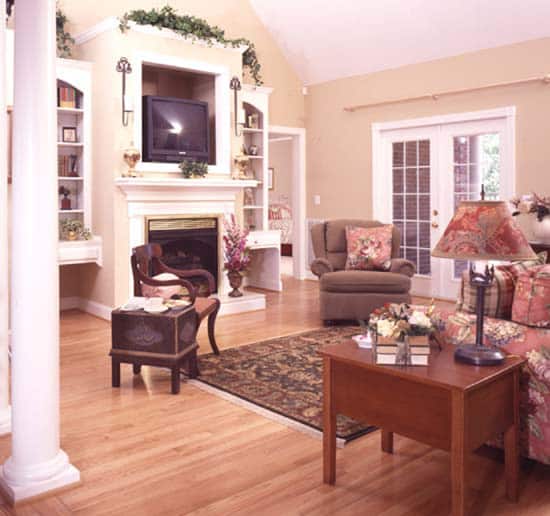 客厅里有布质座椅、木桌和一座壁炉，壁炉顶部装有一台电视。