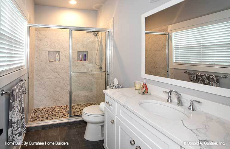 浴室有一个大理石梳妆台，一个厕所，和一个用滑动玻璃门封闭的步入式淋浴。