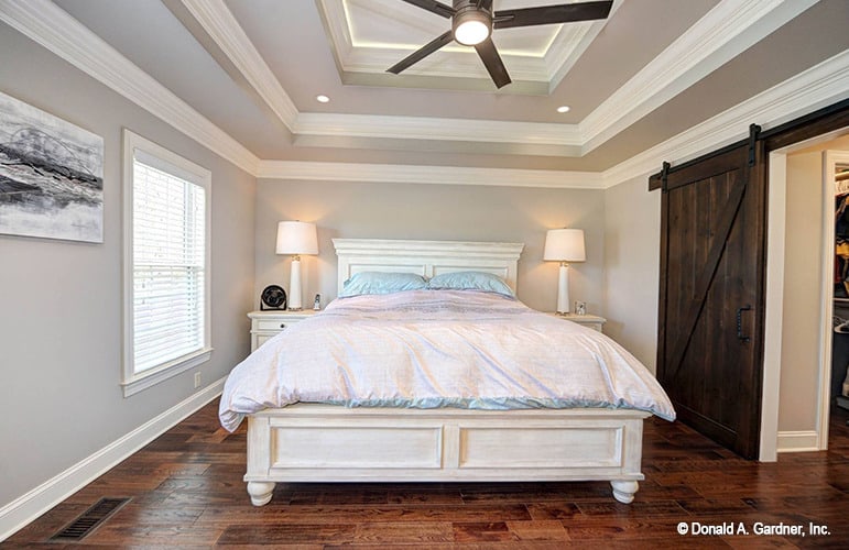 主卧室的特点是白色的家具和一个可爱的阶梯天花板，天花板上安装了一个铁吊扇。