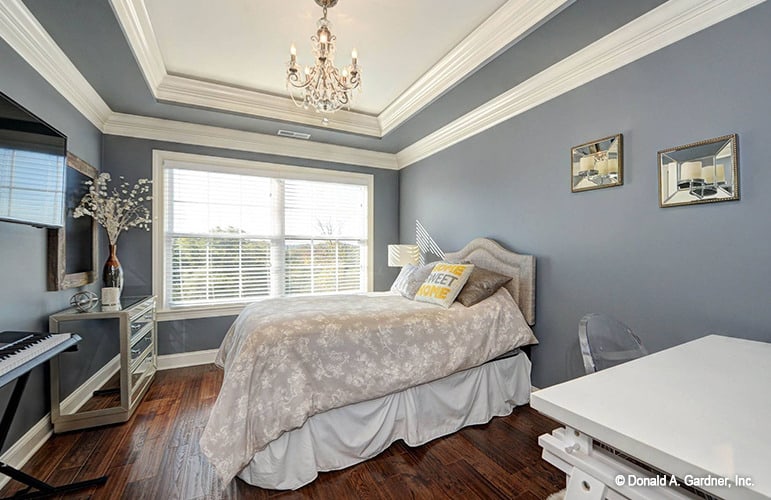 另一间卧室有托盘天花板、硬木地板和衬有白色装饰的灰色墙壁。