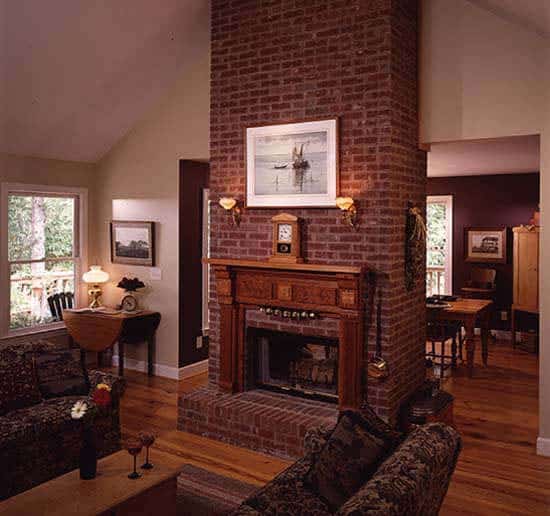 大房间里有花沙发，一张木制咖啡桌，拱形天花板下有一座砖砌壁炉。