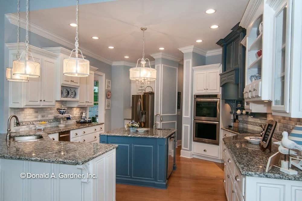厨房提供白色橱柜、花岗岩台面和一个配有水槽和洗碗机的中央岛台。