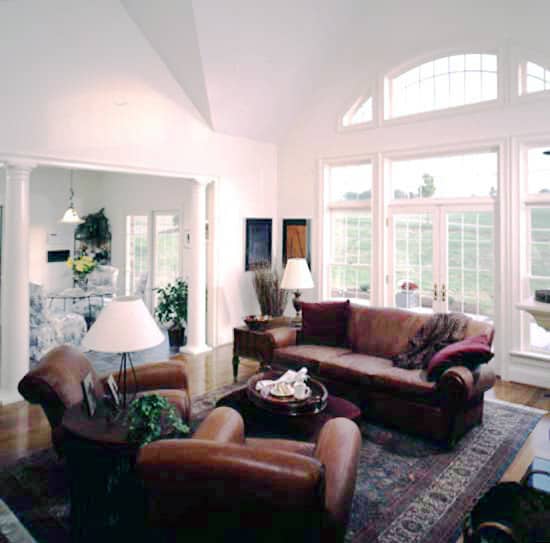 家庭娱乐室里有棕色真皮座椅和一面墙的窗户，可以让充足的自然光照进来。