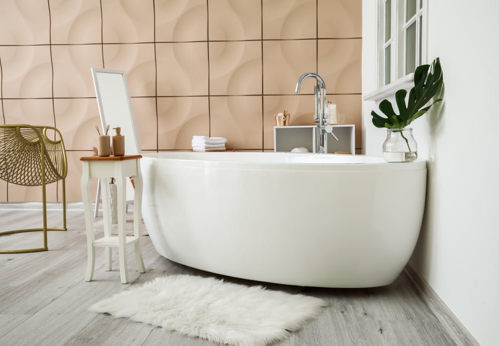 浴室里有一个白色的独立浴缸，靠着米色的镶板墙。