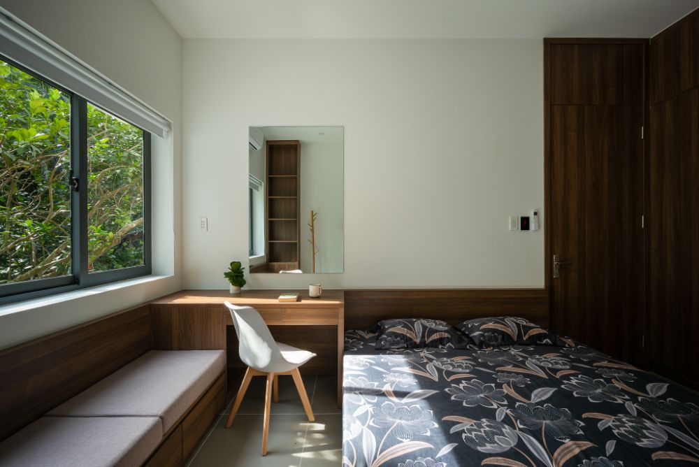卧室设有胡桃木床，橱柜，桌子和沙发，在一个打开的窗口，可以看到外面。