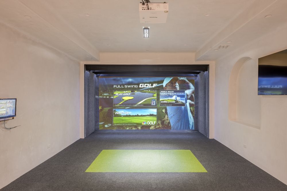 房间宽屏幕上高尔夫模拟器在灰色的地毯和漆成白色的墙壁和天花板。