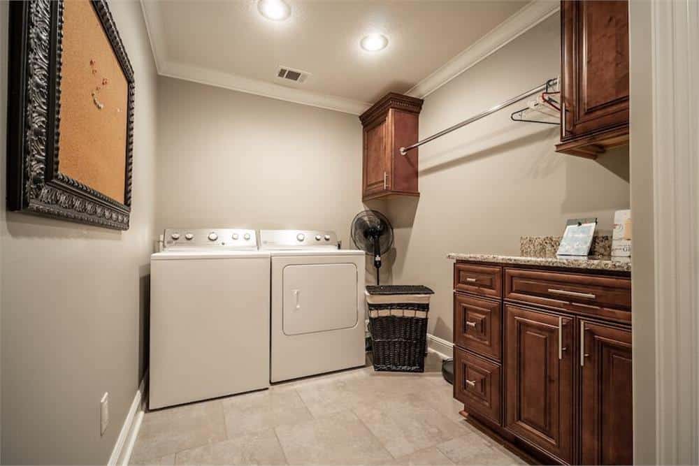 洗衣房配有白色洗衣机和烘干机，木制橱柜和花岗岩台面。