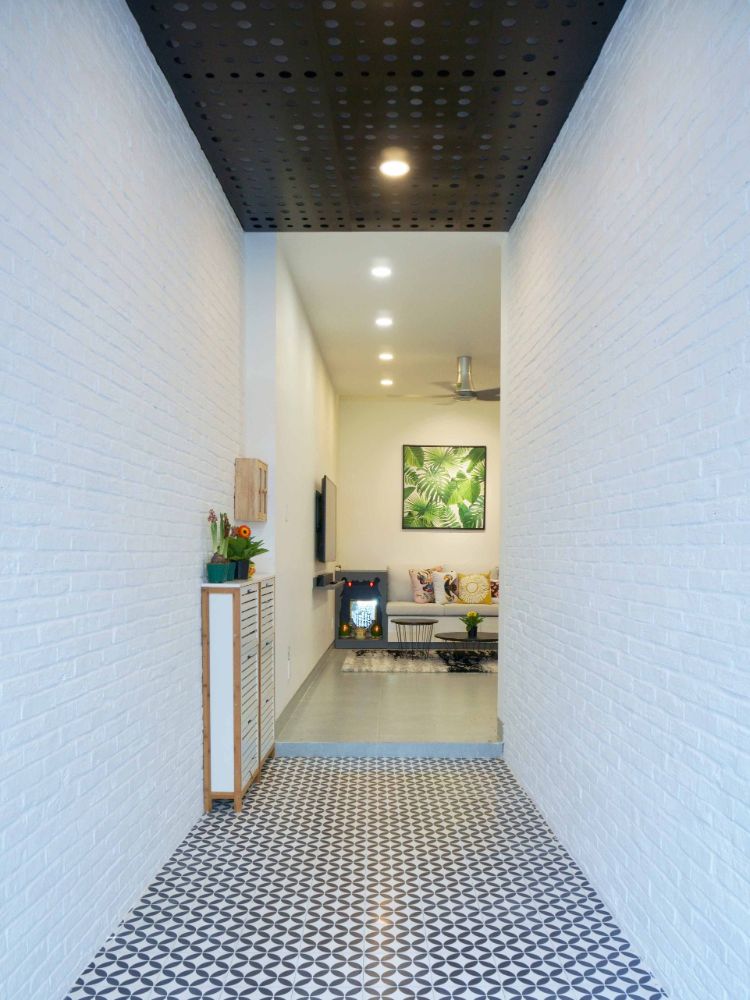 客厅的入口有木制门厅，白色的实心砖墙和有图案的瓷砖地板。