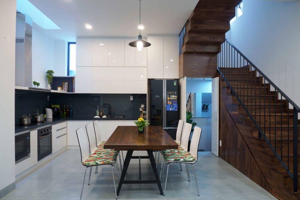 餐厅和厨房区采用极简主义家具设计，用于楼梯下的存储。