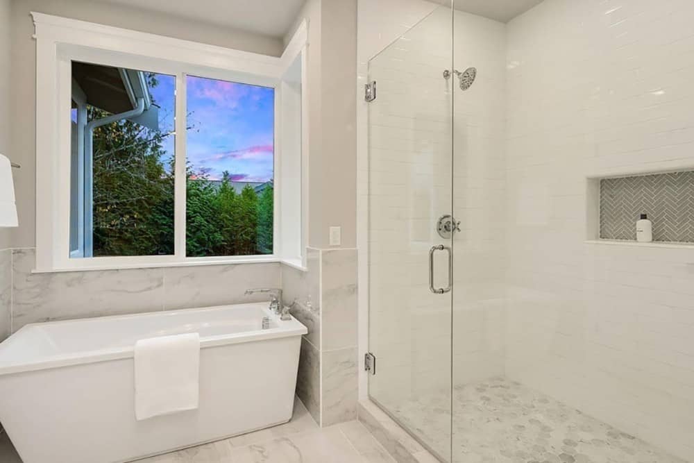 主浴室带有步入式淋浴和独立浴缸，位于滑动窗下。