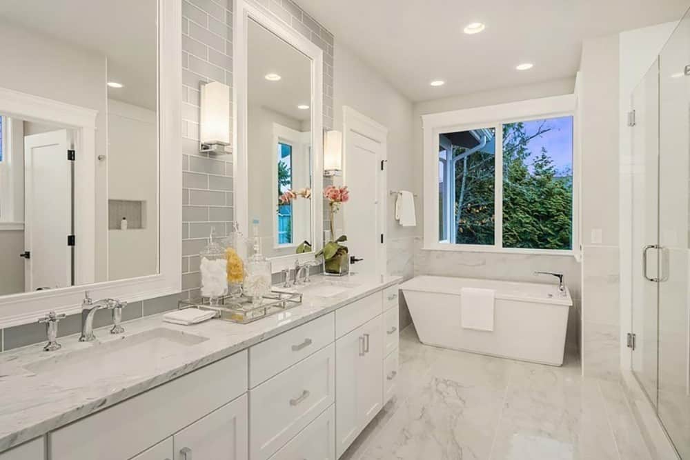 主浴室包括一个带有白色镜框镜子和线性烛台的双洗手台。