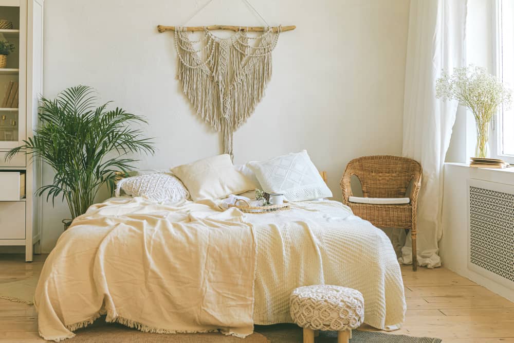 热带风格的卧室，有新鲜的盆栽和挂在床上的流苏。