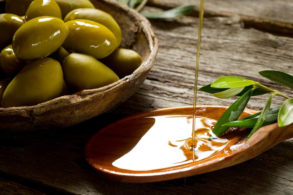轻橄榄油倒在一个大木勺上。