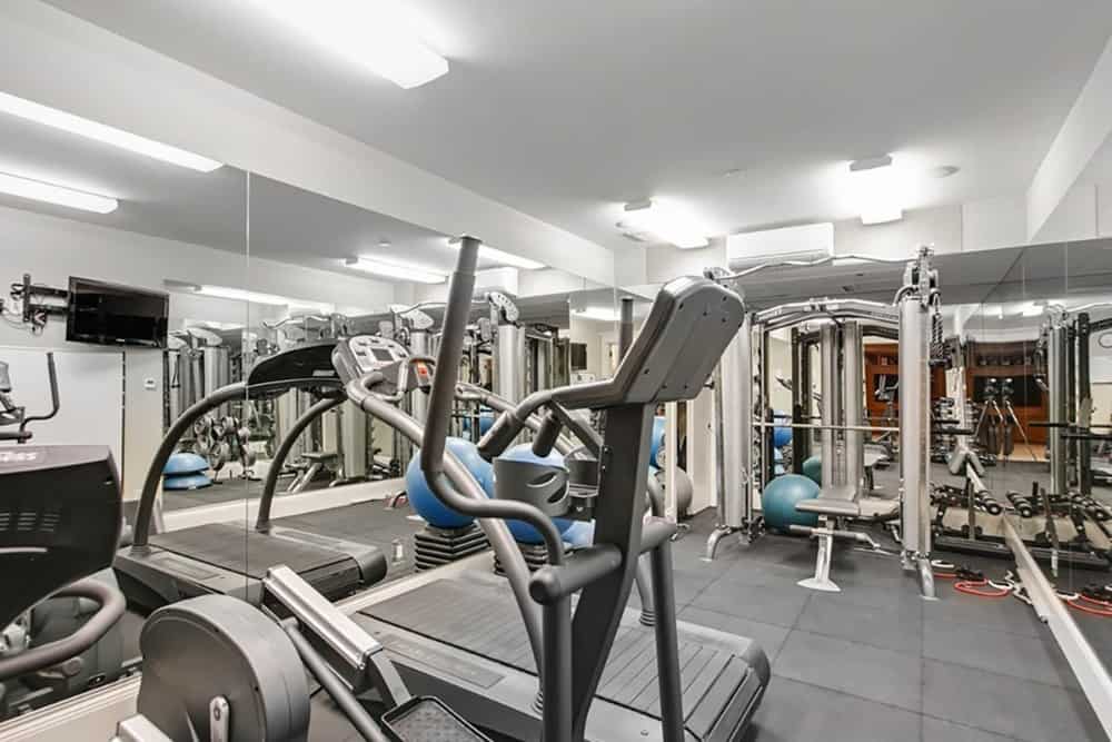 一个设备齐全的健身房，有瓷砖地板和很多很酷的线形灯。