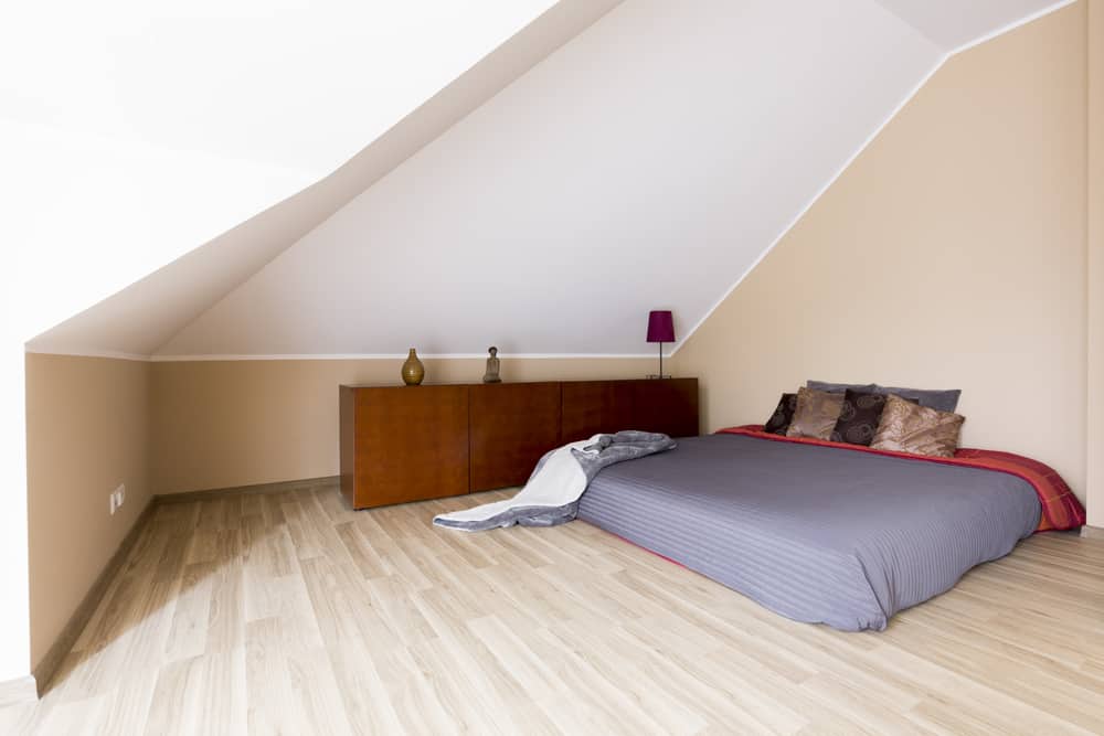 有拱形天花板的卧室，浅色硬木地板上有床垫。
