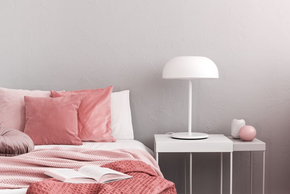 粉红色的床搭配白色的嵌套床头柜。