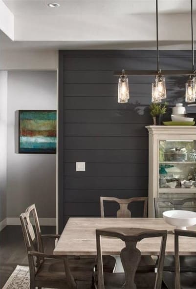 餐厅设有木制餐厅，线性吊灯，展示柜放置在灰色镶板强调墙。