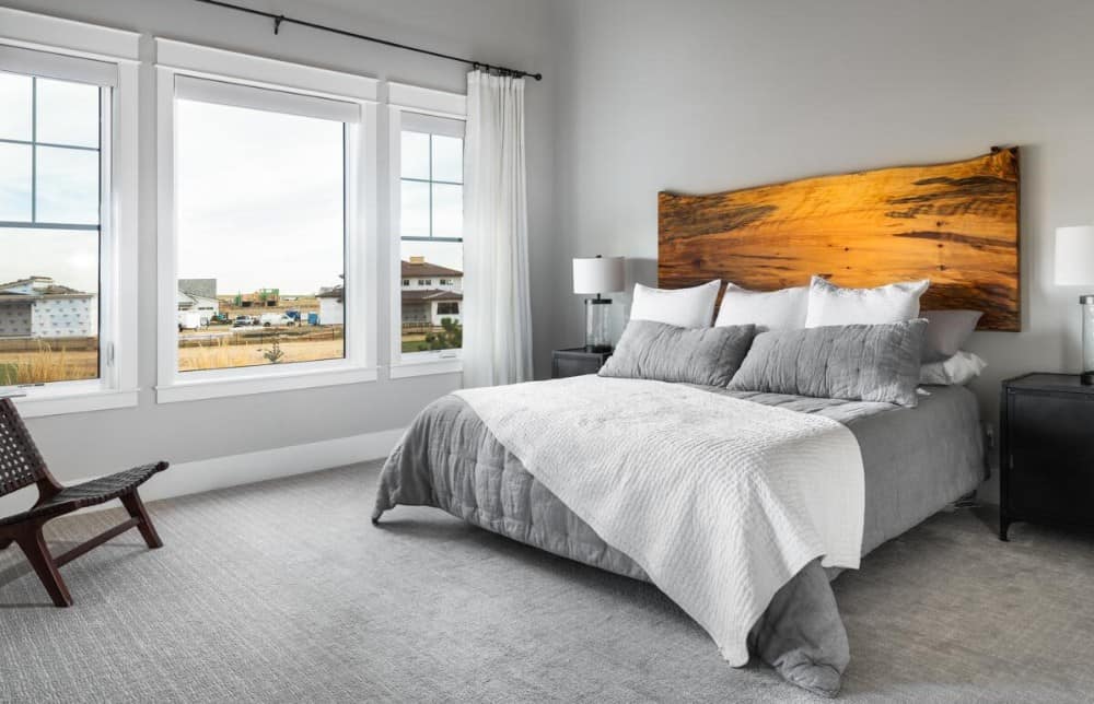 主卧室有地毯地板和一张舒适的床，配有定制的木床头板。