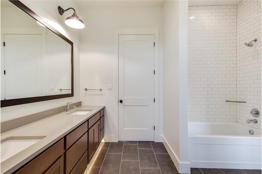 另一间浴室有双洗手池梳妆台，浴缸和淋浴组合，后挡板是白色的地铁瓷砖。