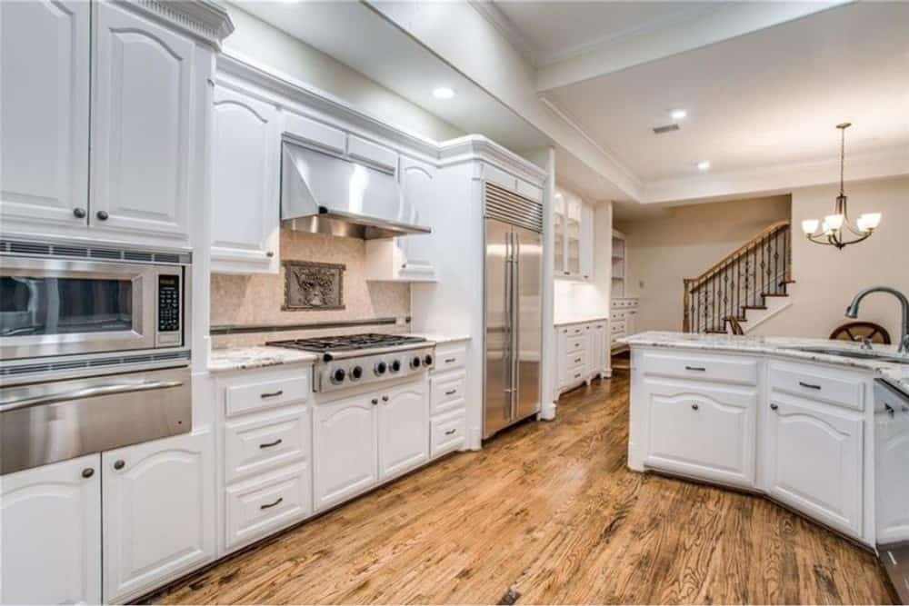 厨房配有不锈钢电器，白色橱柜和花岗岩台面。