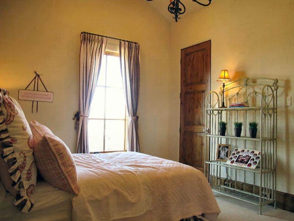 另一间卧室有拱形天花板，铺着地毯的地板，还有一扇大窗户，吸引自然光进来。