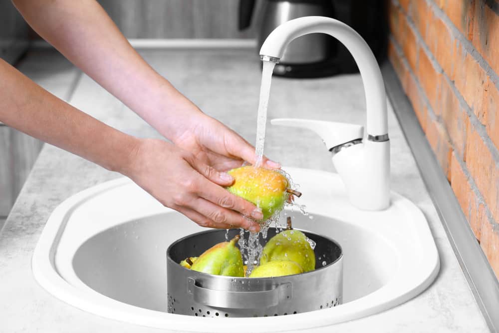 女人在厨房水池里洗梨。