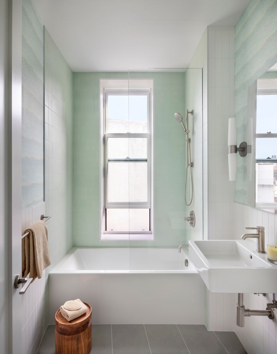 Skylit Master Bath在淋浴时有一个Perlato固体表面浴缸，Farrow和Ball Yukutori壁纸和Vermeere Hex Mosaics。