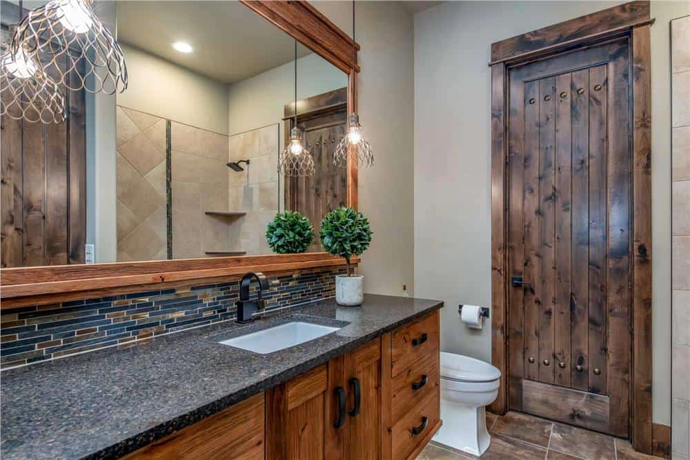 这间浴室设有一个大梳妆台、一个马桶和一个可以从长方形镜子中反射出来的步入式淋浴间。