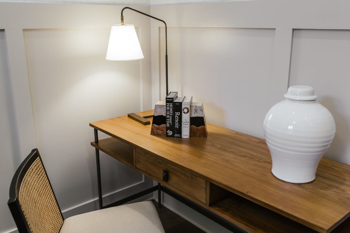 卧室迷你办公室有一张书籍，光和一个白色瓶子的木桌。